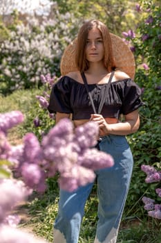 portrait of young woman with long hair outdoors in blooming lilac garden.