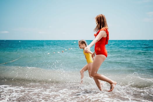 Happy loving family mother and daughter having fun together on the beach. Mum playing with her kid in holiday vacation next to the ocean - Family lifestyle and love concept.