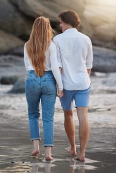 Couple walking on beach, holding hands and travel with love and commitment in relationship, adventure and romance. Trust, partnership and care with people outdoor, tropical holiday and back view.