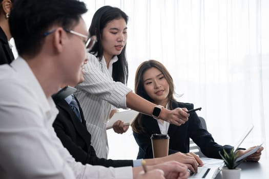 Harmony in office concept as business people analyzing dashboard paper together in workplace. Young colleagues give ideas at manager desk for discussion or strategy planning about project.