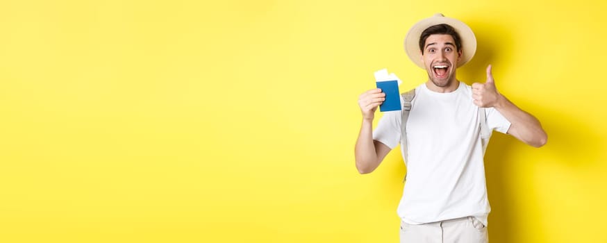 Tourism and vacation. Satisfied male tourist showing passport with tickets and thumb up, recommending travel company, standing over yellow background.