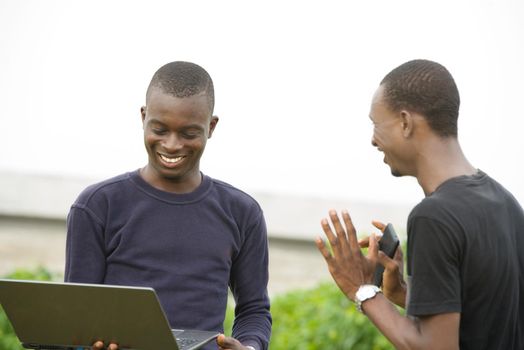 young people standing with computer laughing.