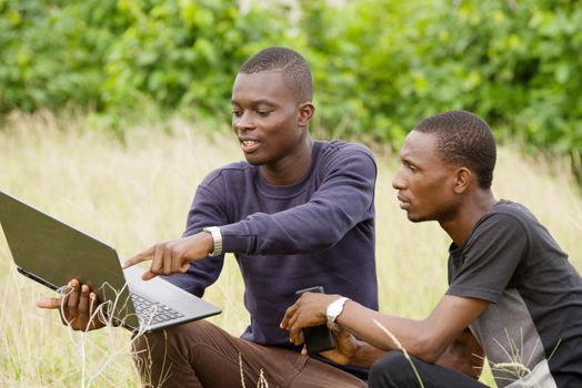 two young students discuss and plan their work on a laptop in nature..
