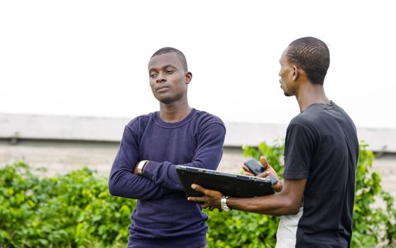 Young people standing with one laptop and talking to each other.