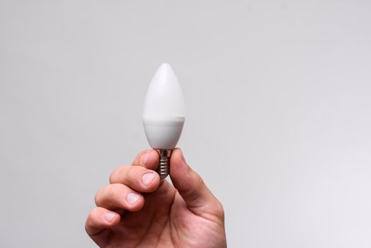 LED lamp in the shape of a candle in the hand on a white background. close-up.