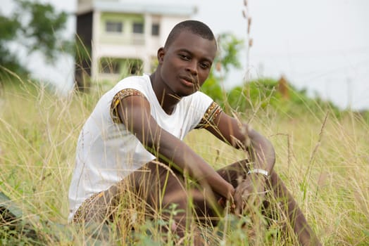 Portrait of a pensive young man relaxing sitting alone in the grass