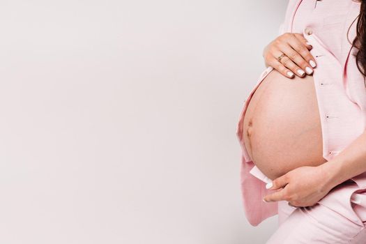 pregnant woman in a suit close-up on a gray background.