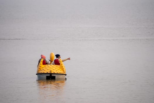 people enjoying a pedal boat decorated beautifully on the landmark sukhna lake in chandigarh with more boats in the distance showing this popular tourist spot