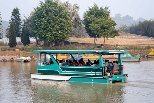 Chandigarh, Punjab, India -circa 2023: people enjoying a pedal boat decorated beautifully on the landmark sukhna lake in chandigarh with more boats in the distance showing this popular tourist spot