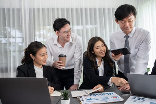 Harmony in office concept as business people analyzing dashboard paper together in workplace. Young colleagues give ideas at manager desk for discussion or strategy planning about project.