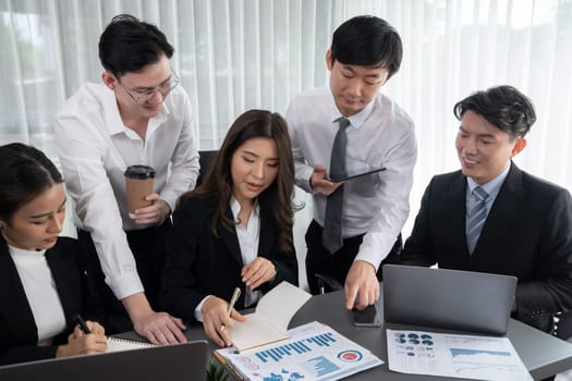 Harmony in office concept as business people analyzing dashboard paper together in workplace. Young colleagues give ideas at manager desk for discussion or strategy planning about project.
