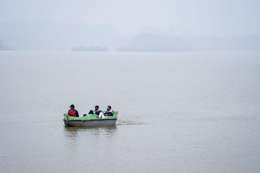 Chandigarh, India - circa 2023: people enjoying a pedal boat decorated beautifully on the landmark sukhna lake in chandigarh with more boats in the distance showing this popular tourist spot