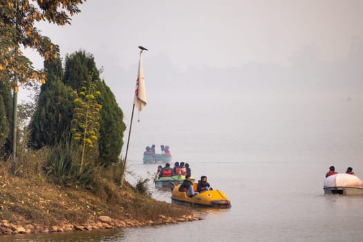 Chandigarh, Punjab, India -circa 2023: people enjoying a pedal boat decorated beautifully on the landmark sukhna lake in chandigarh with more boats in the distance showing this popular tourist spot