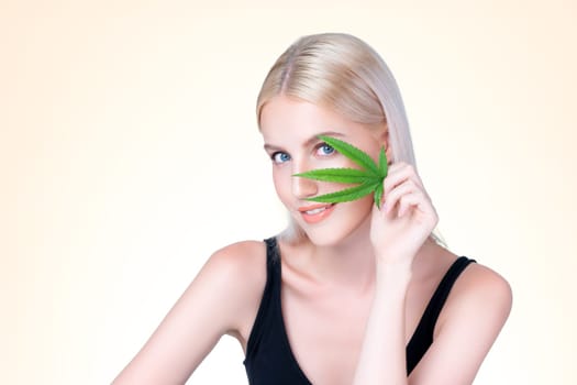Personable beautiful white blond hair with perfect smooth makeup skin hold cannabis green hemp in isolated background for natural CBD skincare treatment with expressive facial and gesture expression.