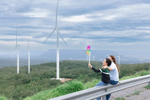 A progressive mother and her son are on vacation, enjoying the natural beauty of a lake at the bottom of a hill while the boy carries a toy windmill.