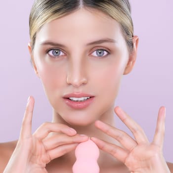 Closeup alluring beautiful female model applying powder puff for facial makeup concept. Portrait of flawless perfect cosmetic skin woman put powder foundation on her face in pink isolated background.