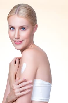 Closeup personable beautiful woman putting skincare moisturizer cream on her arm looking in camera in isolated background as concept for beauty care treatment. Female model applying lotion on her body