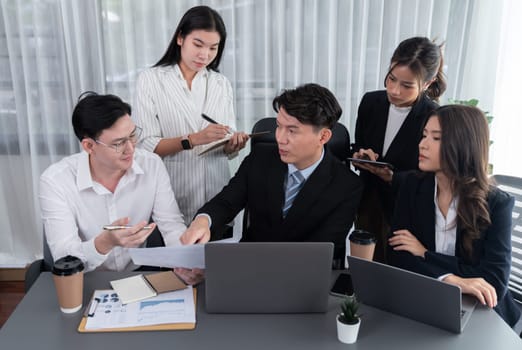 Harmony in office concept as business people analyzing dashboard paper together in workplace. Young colleagues give ideas at manager desk for discussion or strategy planning about project.