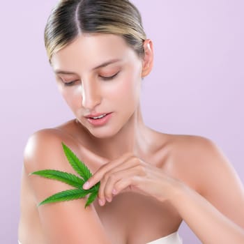 Alluring beautiful woman model portrait holding green leaf as concept for cannabis skincare cosmetic product for perfect skin freshness treatment in isolated pink background.