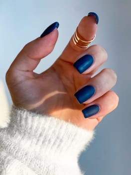 Beautiful nails manicure photo. Dark blue color matte top nail polish. Female hand, rings, closeup photo, aesthetics. Manicure design, square nail shape.Luxury style, Creative beauty photo. Woman hand. High quality photo