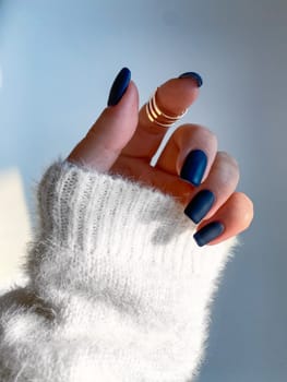 Beautiful nails manicure photo. Dark blue color matte top nail polish. Female hand, rings, closeup photo, aesthetics. Manicure design, square nail shape.Luxury style, Creative beauty photo. Woman hand. High quality photo