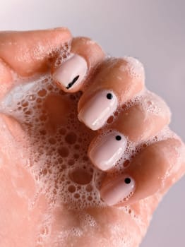 Soap foam manicure nails hand. Beautiful nails manicure photo. Nude top nail polish. Female hand, closeup photo, cleaning hands. Manicure design, square nail shape. Creative beauty photo, hand washing. High quality photo