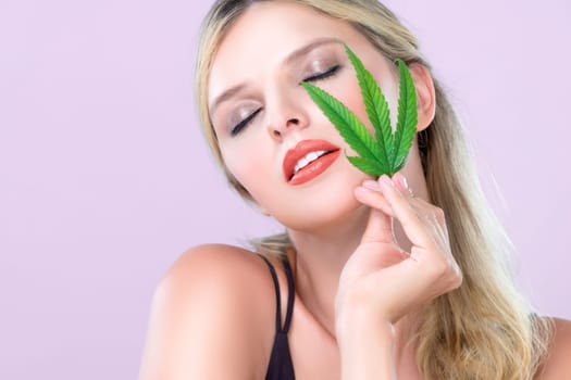 Closeup alluring beautiful woman portrait with perfect makeup lip stick, eyeshadow hold green leaf as concept for cannabis skincare cosmetic product for skin freshness treatment in isolated background