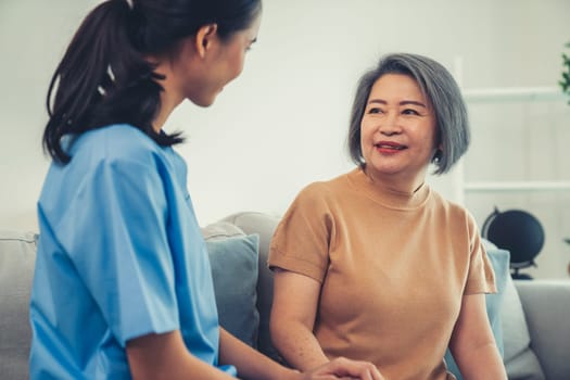 A contented senior woman visited by her personal caregiver and hold each other's hands.