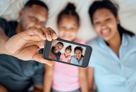 Phone, selfie and portrait of family on bed for fun, happiness and relaxing in morning. Black family, love and photo on screen of dad using smartphone with mom and girl in bedroom, enjoying weekend.