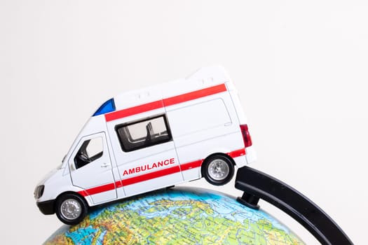 Globe and ambulance toy car on gray background close up