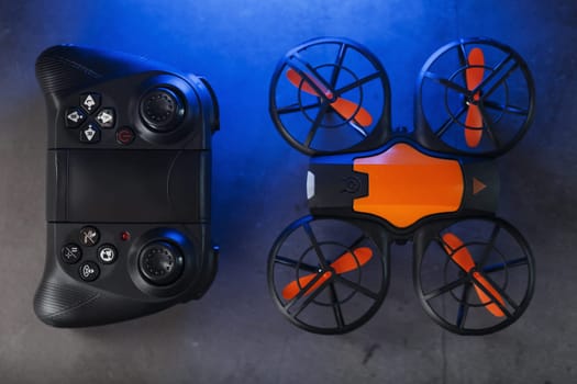 Gaming orange mini drone on a dark background for control from a gamepad