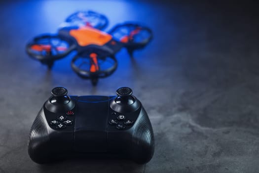 Gaming orange mini drone on a dark background for control from a gamepad
