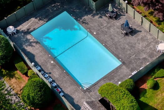 Outdoor swimming pool with emerald water, metal rails on side, and recreation area around