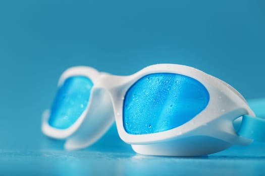 White swimming goggles on a blue background in a minimalist style with free space