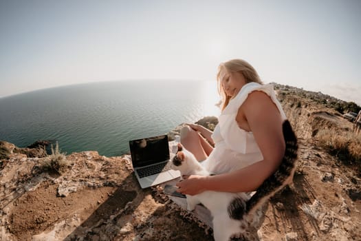 Woman sea laptop. Business woman in yellow hat working on laptop by sea. Close up on hands of pretty lady typing on computer outdoors summer day. Freelance, digital nomad, travel and holidays concept.