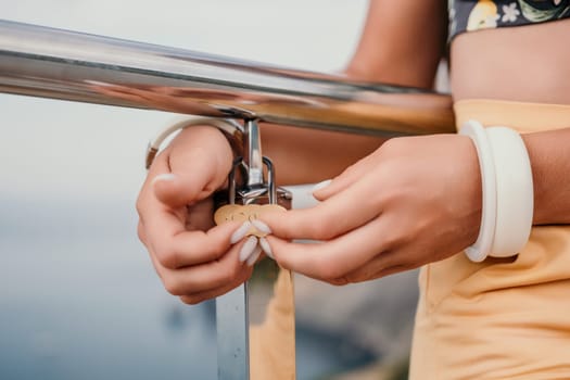 Hand, lock, heart, love, valentines day. Close up view of a woman holding a heart shaped lock that is locked onto a chain link fence.