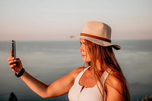 Woman travel sea. Happy tourist in hat enjoy taking picture outdoors for memories. Woman traveler posing on the beach at sea surrounded by volcanic mountains, sharing travel adventure journey