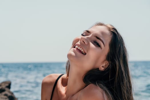 Woman travel sea. Young Happy woman in a long red dress posing on a beach near the sea on background of volcanic rocks, like in Iceland, sharing travel adventure journey