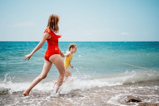 Happy loving family mother and daughter having fun together on the beach. Mum playing with her kid in holiday vacation next to the ocean - Family lifestyle and love concept.