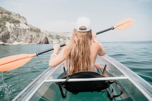 Woman in kayak back view. Happy young woman with long hair floating in transparent kayak on the crystal clear sea. Summer holiday vacation and cheerful female people having fun on the boat.
