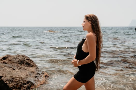 Woman travel sea. Young Happy woman in a long red dress posing on a beach near the sea on background of volcanic rocks, like in Iceland, sharing travel adventure journey