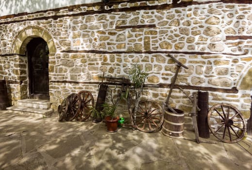 old stone house with vintage things and wooden wheels