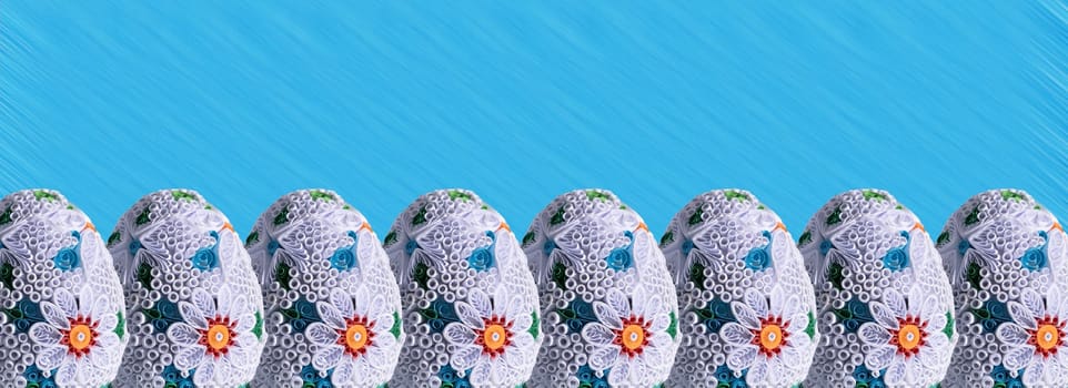 Many Easter eggs lined up one next to the other and the whole composition is set against a solid blue background.