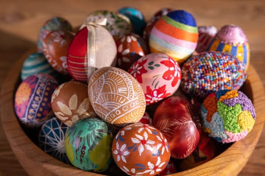 Top view of a wooden bowl filled with colorful Easter eggs. Easter composition with a view to adding graphic elements on your own.