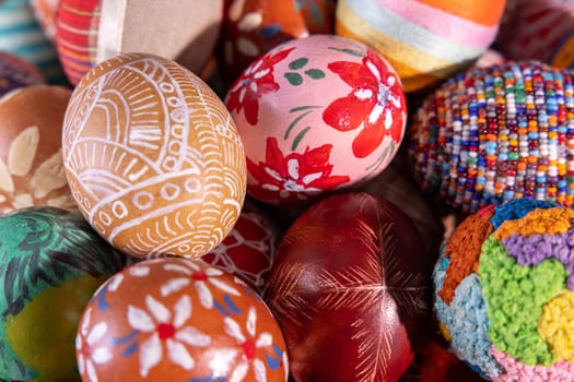 Close-up view from above. Randomly stacked close together, the Easter eggs form a colorful Easter composition while tightly filling the entire frame.