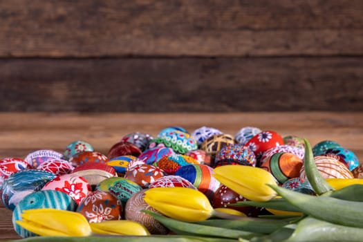 Easter composition allowing you to put your own graphic content on a free field. Yellow tulips and Easter eggs in the foreground and fuzzy boards in the background.