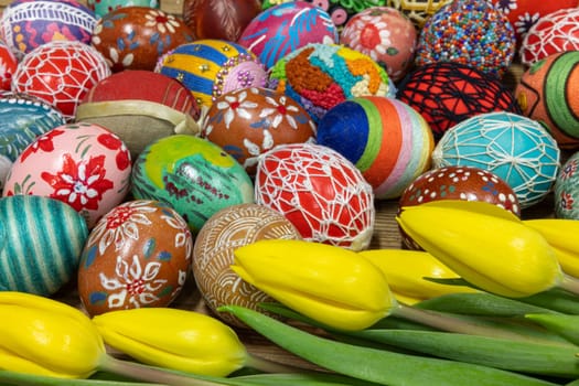An aerial view of tightly stacked colorful Easter eggs and yellow tulips forming a distinctive composition for Easter Worlds.