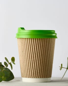 Paper brown cups with a plastic green lid for coffee and tea on a white background