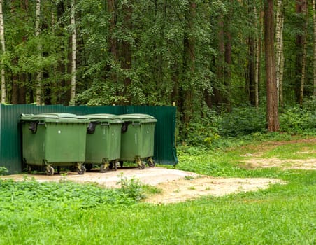 Photo garbage collection containers on the background of a green forest. Conscious consumption and concern for the environment.