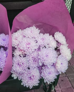 Beautiful gift bouquets of chrysanthemums in brown kraft paper, on the counter of a flower shop, vertical.